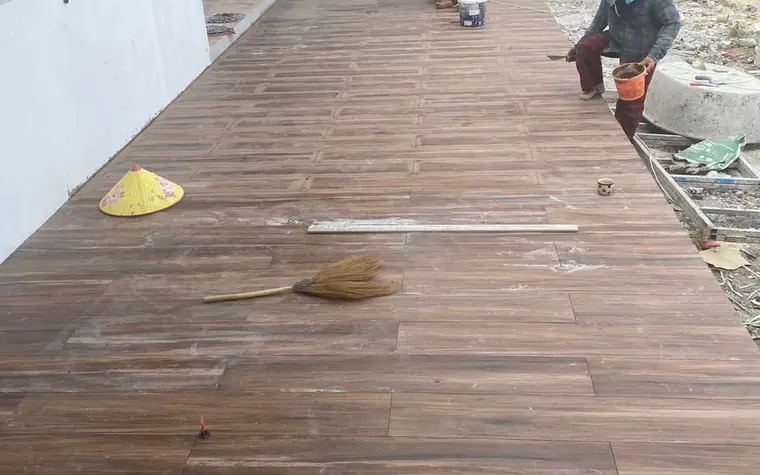 ช่างกำลังปูกระเบื้องลายไม้ในบ้านที่ยังก่อสร้างไม่เสร็จ